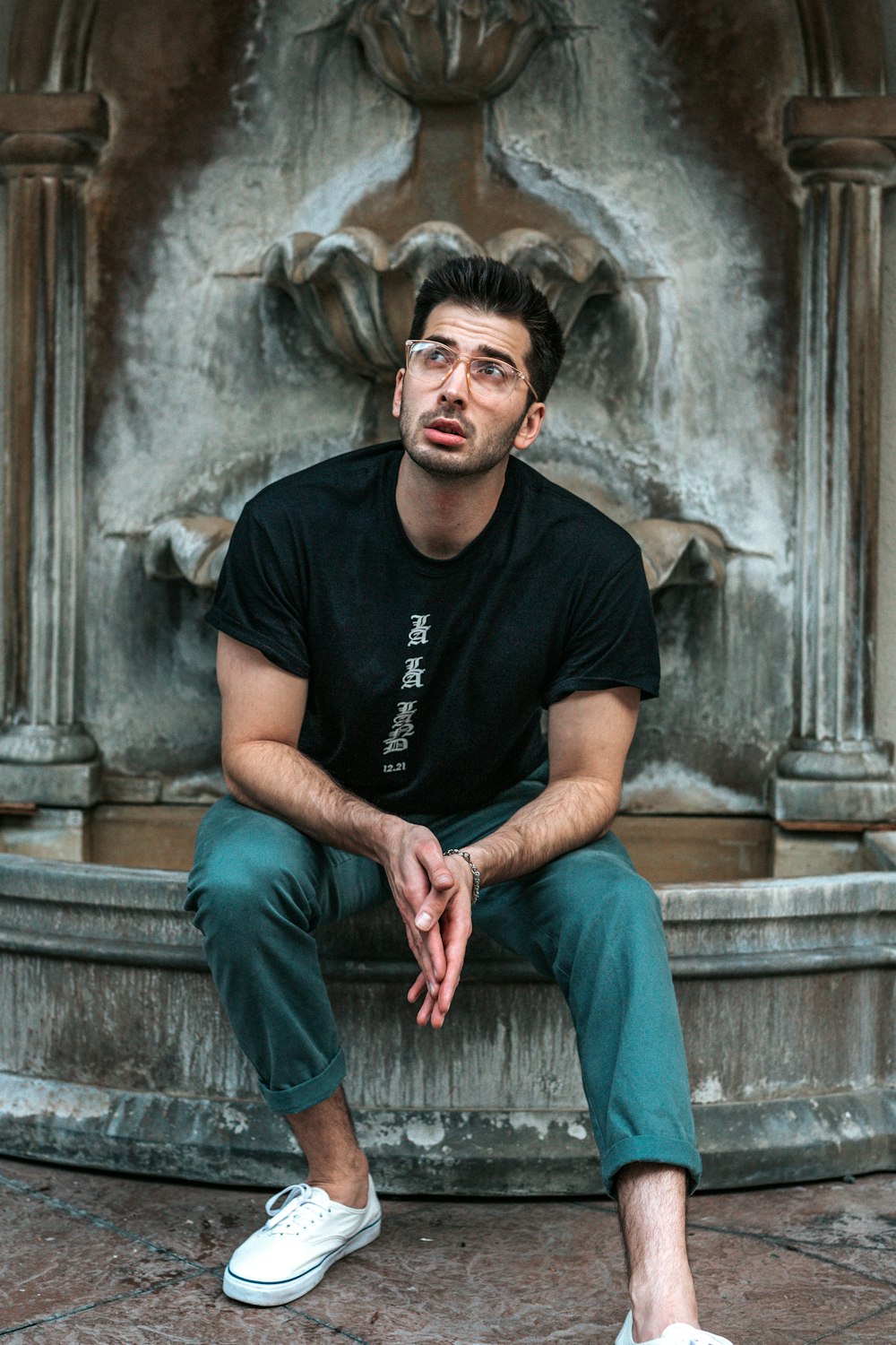 man sitting on gray fountain