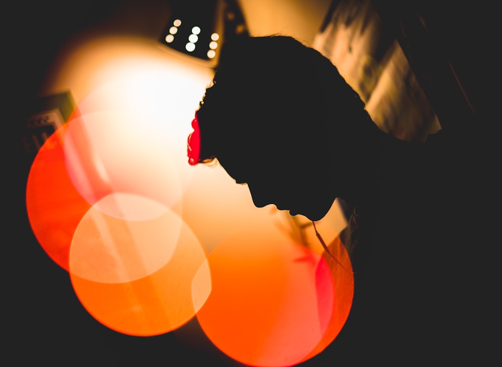 bokeh photography of silhouette of man leaning on wall