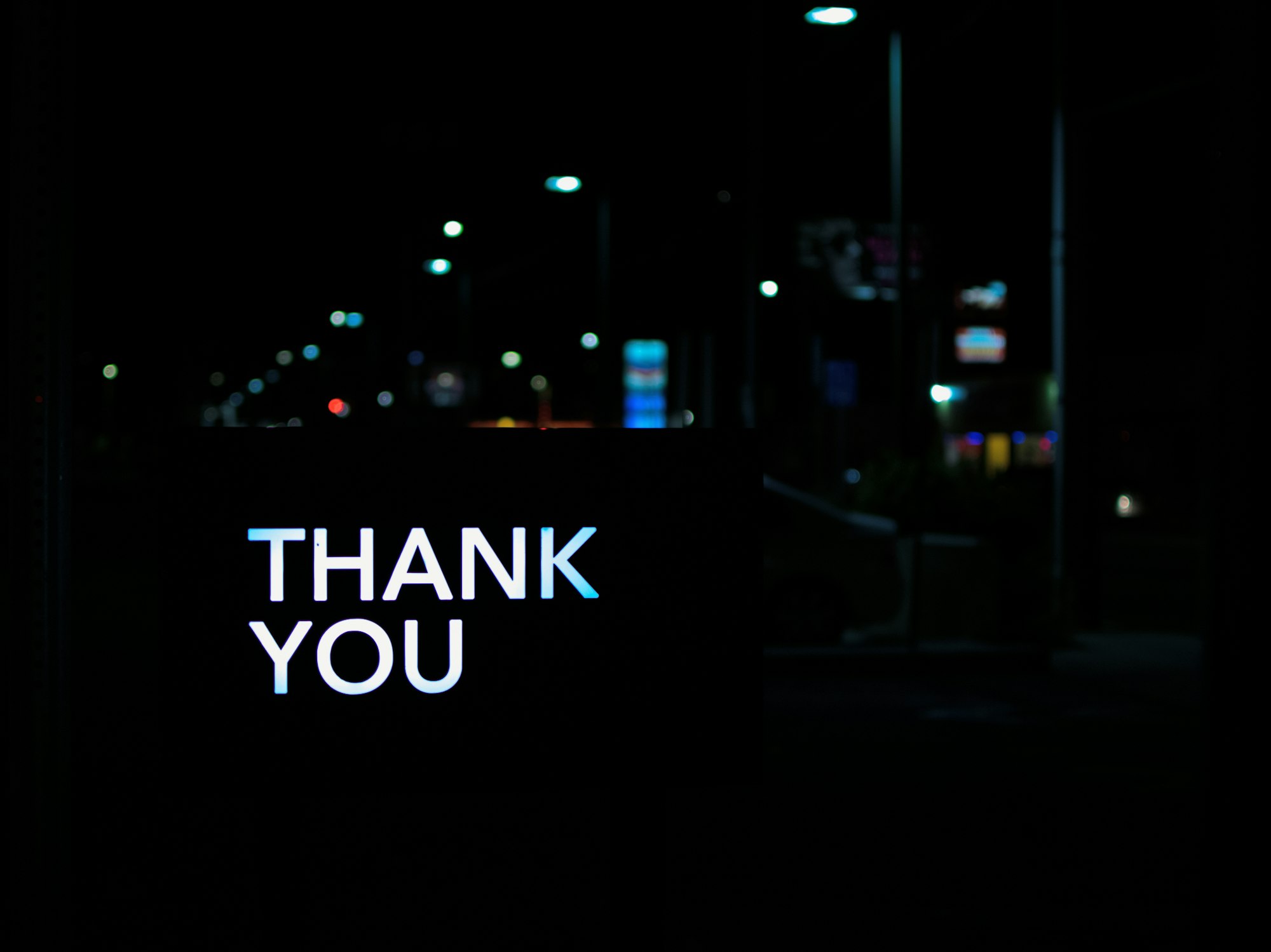 The words "thank you" light up the night on a darkened city street.
