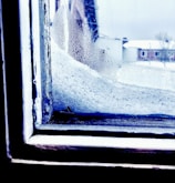 Technician repairing a cracked window pane on a residential home in a snowy Canadian neighborhood.