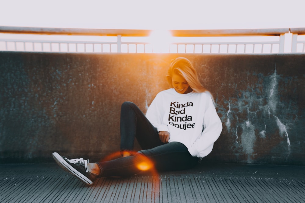 woman sitting and leaning on black wall