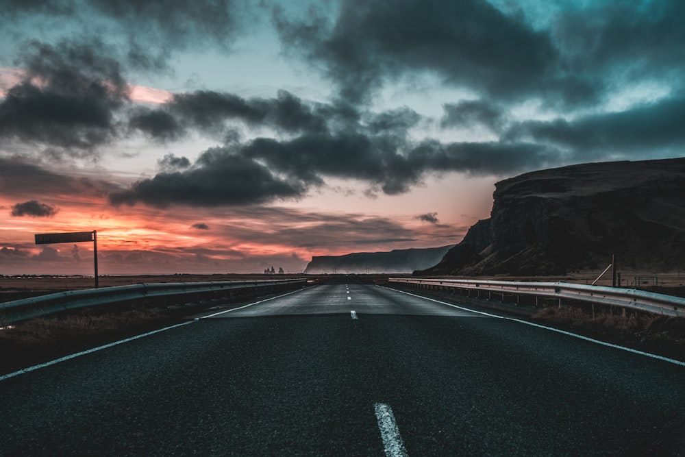road under dark clouds during sunset