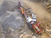 Industrial crusher machine processing basalt rock under a clear sky.