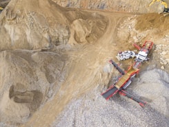 A scene in a quarry with large piles of sand and gravel. Heavy machinery, including trucks and conveyor belts, is visible, indicating active work in the extraction process.