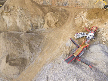 A wide aerial shot showing multiple construction vehicles working in a quarry.