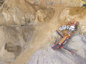 Aerial view of the Pedreira Ervália quarry with heavy machinery working under a clear blue sky.