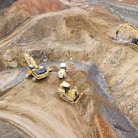 top view photography of four heavy equipment on quarry at daytime