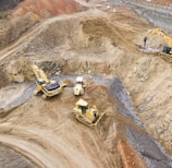 top view photography of four heavy equipment on quarry at daytime