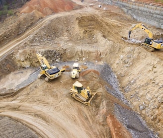 top view photography of four heavy equipment on quarry at daytime