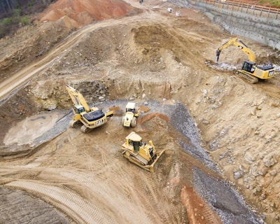 top view photography of four heavy equipment on quarry at daytime