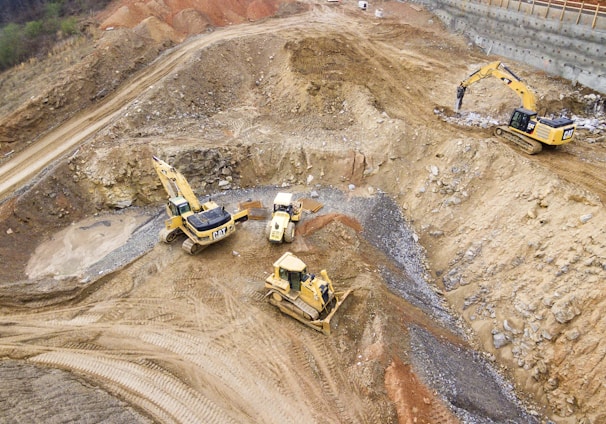 top view photography of four heavy equipment on quarry at daytime