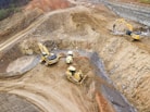 top view photography of four heavy equipment on quarry at daytime