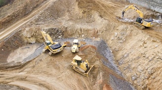 top view photography of four heavy equipment on quarry at daytime