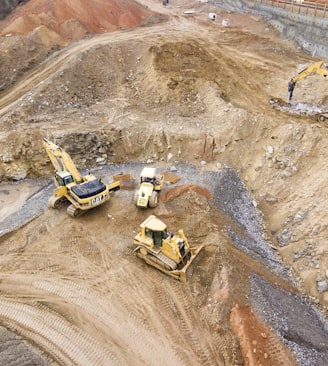 top view photography of four heavy equipment on quarry at daytime