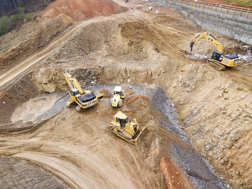 top view photography of four heavy equipment on quarry at daytime