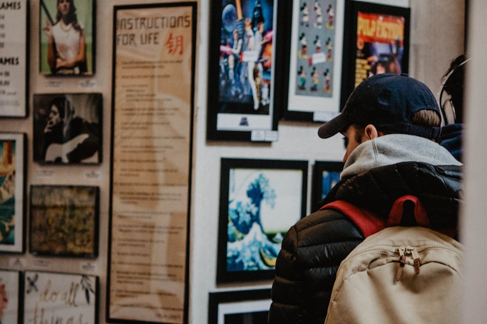 person wearing black bubble jacket watching wall posters