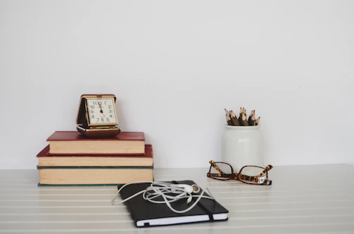 A minimalist workspace featuring a vintage typewriter, glasses, and a stack of published magazines.