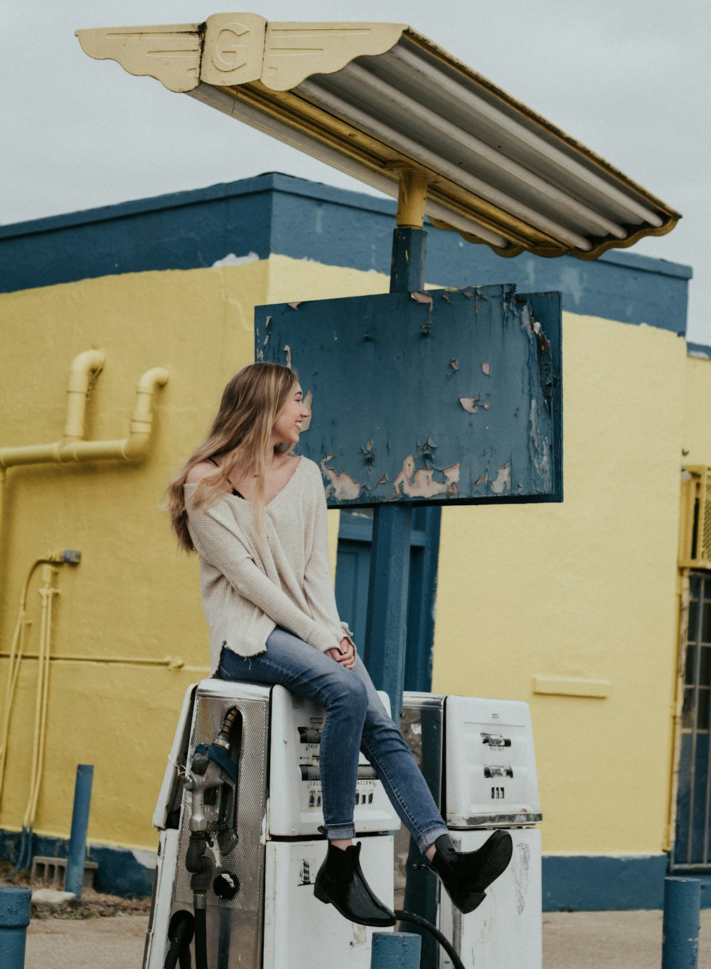 woman sitting on white gasoline pump machine during daytime