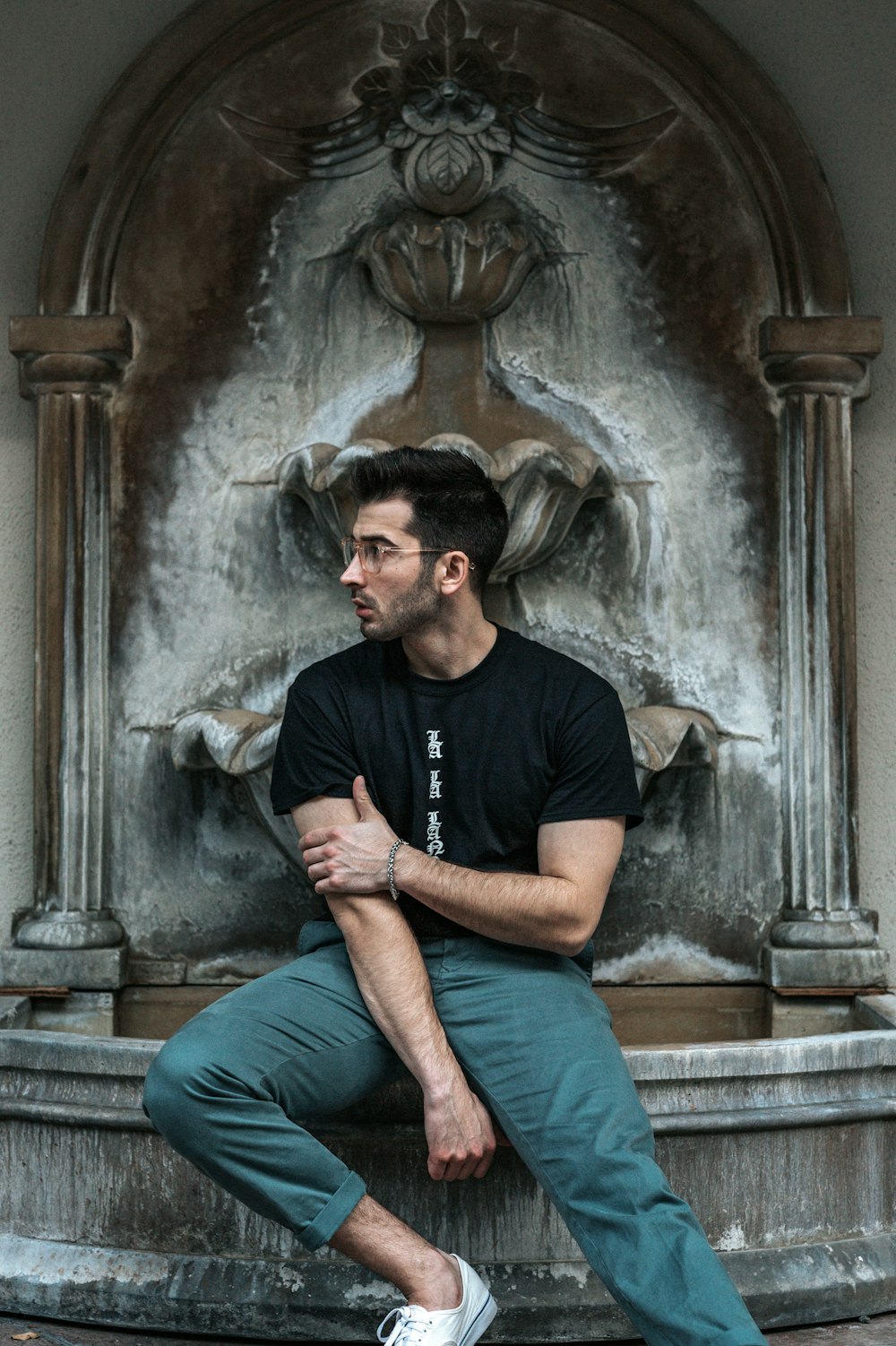 man wearing black shirt sitting near the fountain