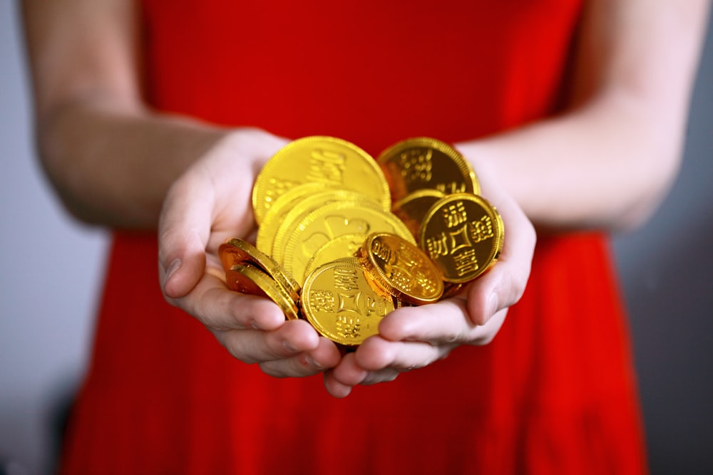 Persona sosteniendo monedas Ching de color dorado