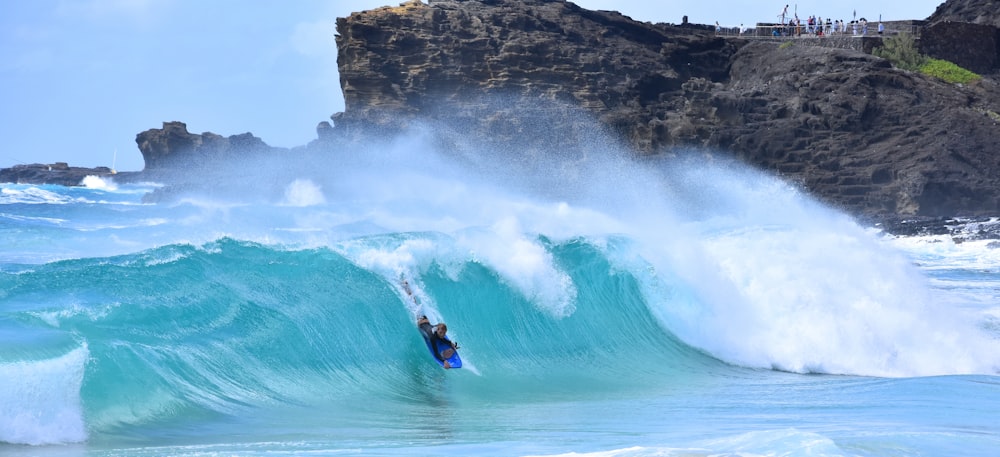 person riding on surfboard on body of water during daytime