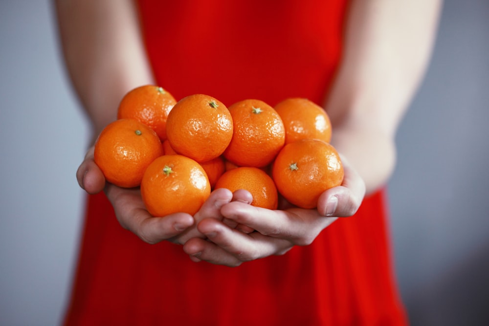 personne tenant des fruits oranges