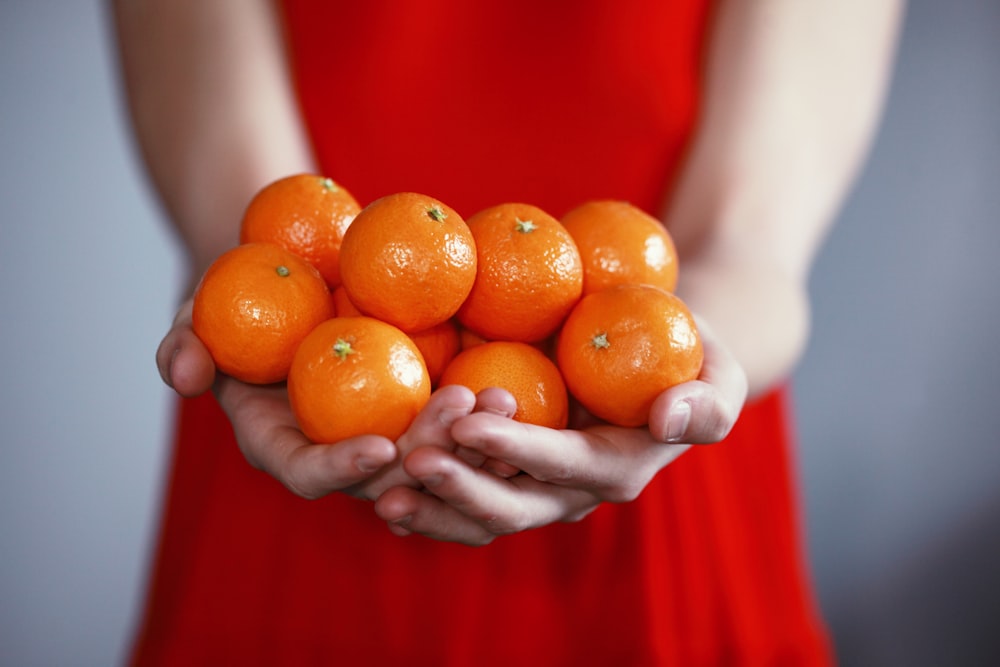 pessoa segurando frutas laranja