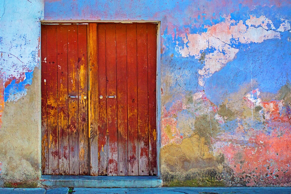 red wooden door of blue, red, and brown painted wall