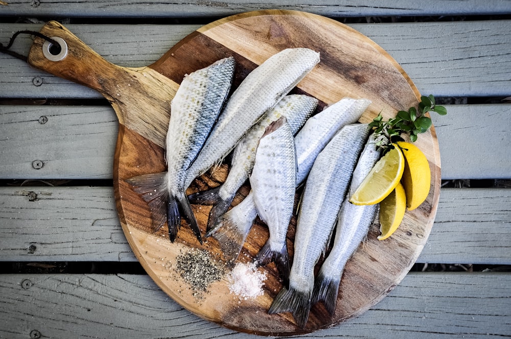 Pescados sin cabeza con rodajas de limones en tabla de cortar de madera marrón