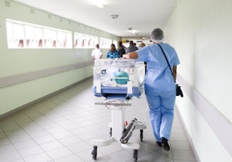 person walking on hallway in blue scrub suit near incubator