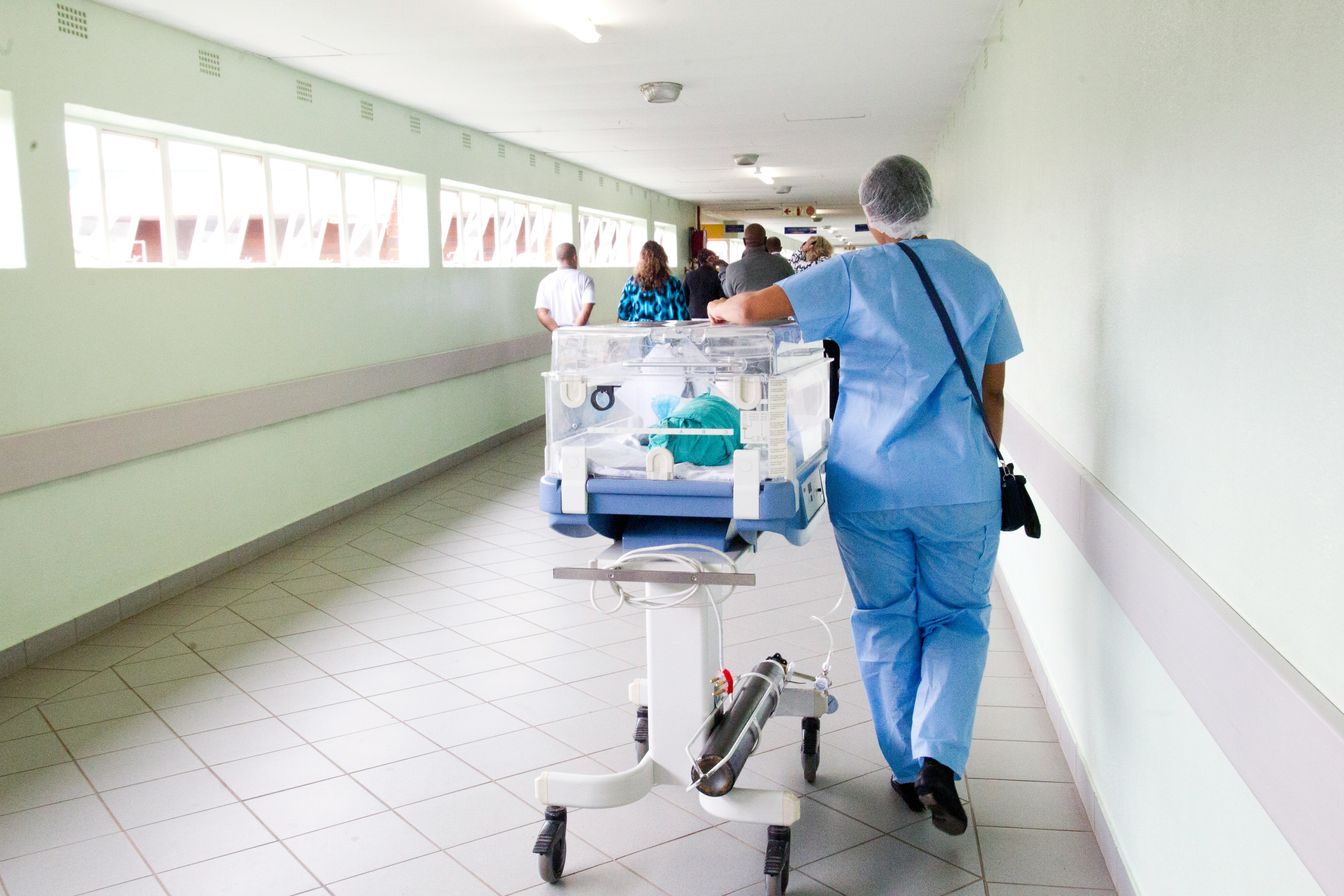 Photo of someone being wheeled on a bed through a hospital 