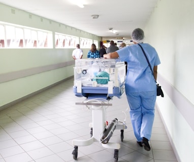 person walking on hallway in blue scrub suit near incubator