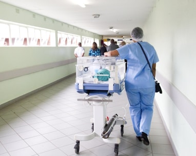 person walking on hallway in blue scrub suit near incubator