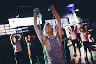 A group training session in a bright gym with people doing resistance exercises.