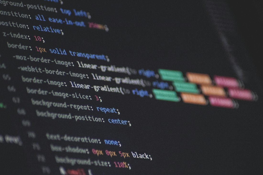 Two developers reviewing code together at a shared desk with two monitors