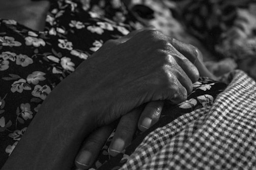 A close-up of weathered hands resting gently on a wooden surface, highlighting fine textures.