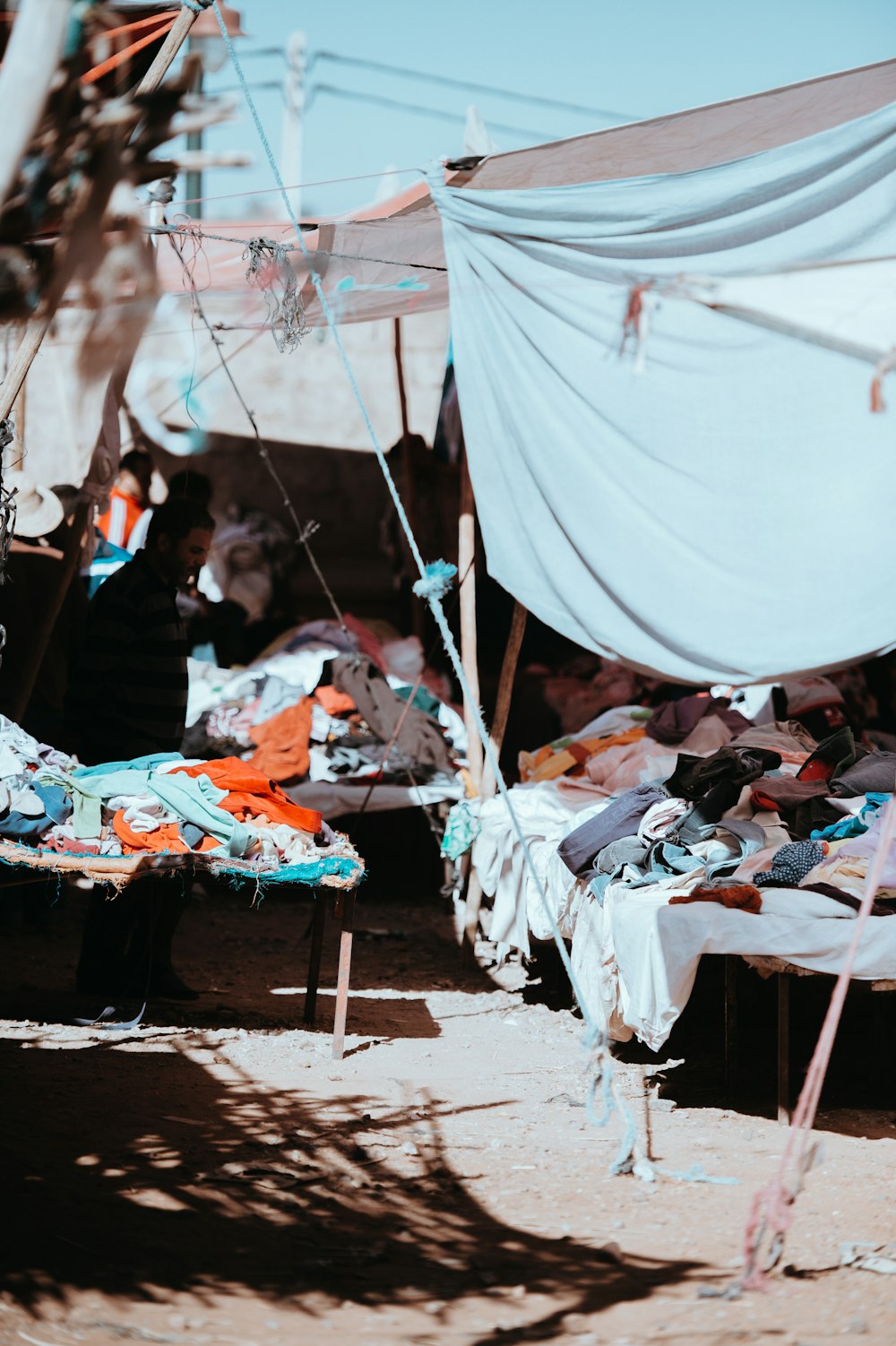 person taking photo of assorted-color clothes market at daytime