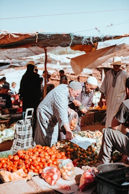 street photography,how to photograph traditional berber market; man picking fruits on stand under white sky during daytime