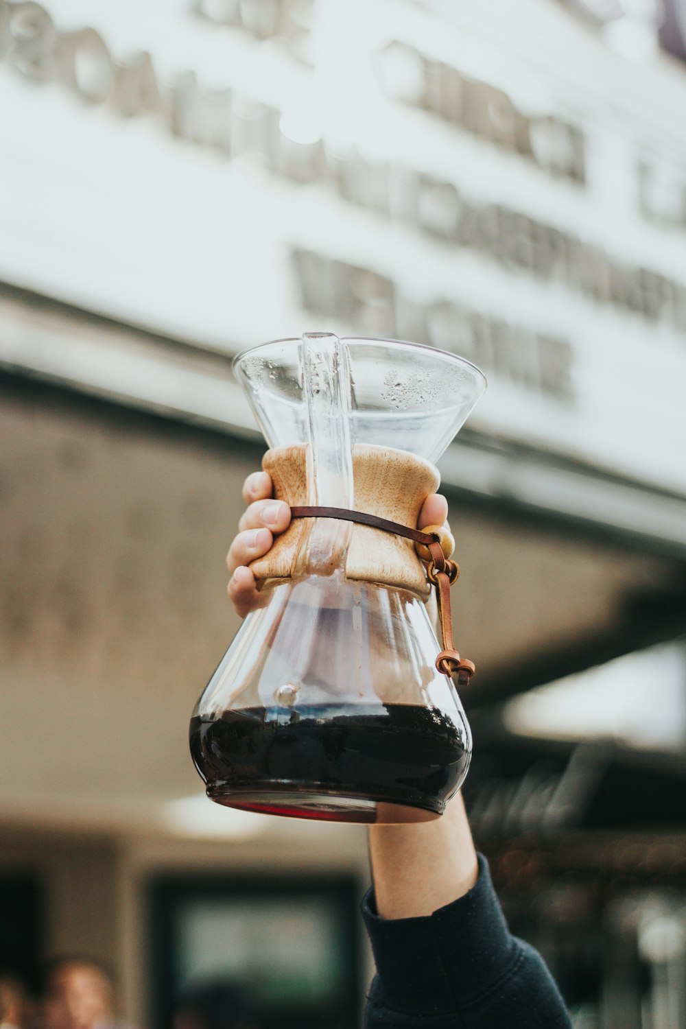 persona sosteniendo una jarra de café de vidrio transparente