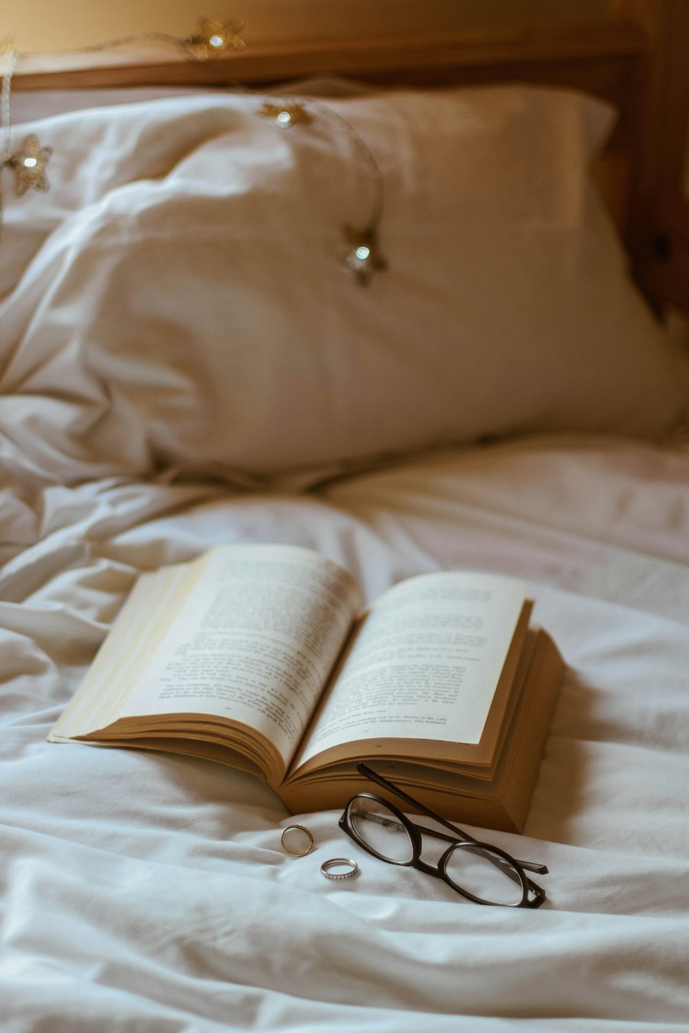 eyeglasses beside book and rings