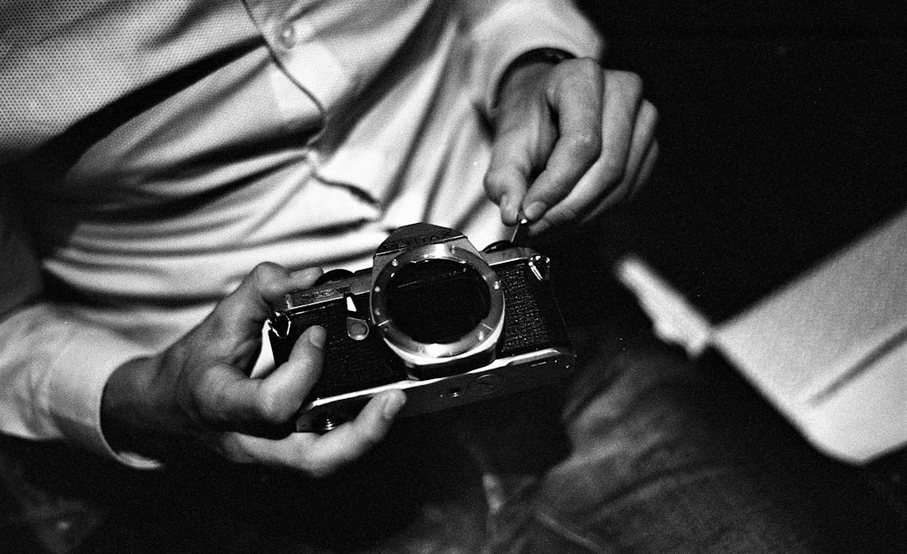 Photographie en niveaux de gris d’un homme tenant un appareil photo