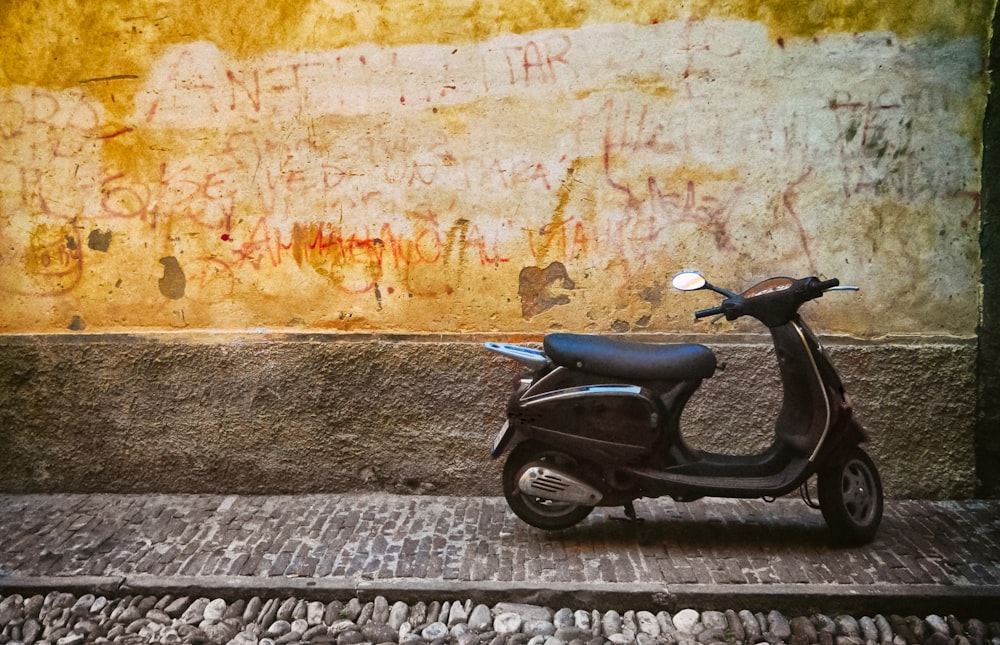 Schwarzer Motorroller in der Nähe der braunen Wand