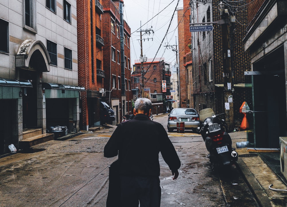 photo of man standing near motorcycle on empty road