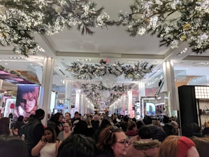 A busy retail store decorated for the holiday season with shoppers browsing products.