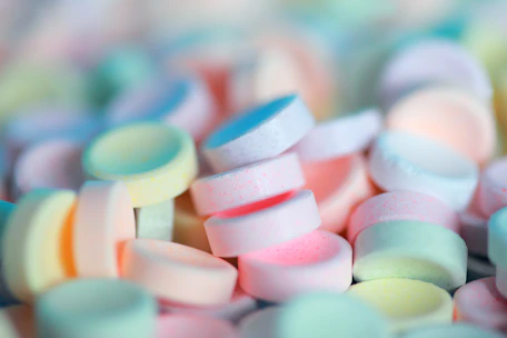 Close-up of colorful caramelized candies shining under soft pink lighting.