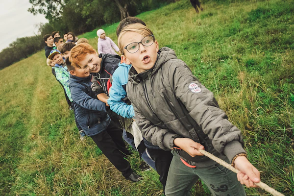 group of children playing tug of war with a rope on an obsticle course.