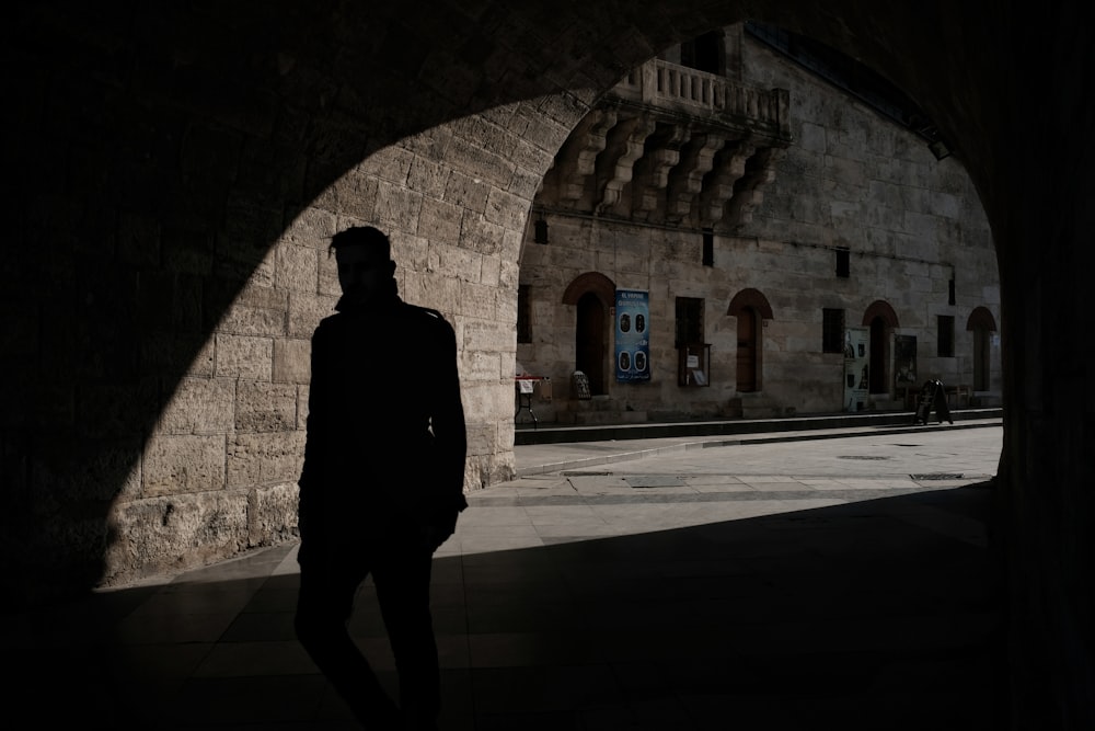 silhouette of man inside of tunnel during daytime