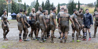 Rugby coaches and players gathered outdoors during a community engagement event.