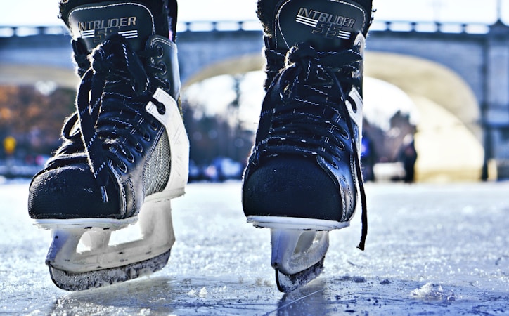 A close up of ice hockey skates resting on the ice, gear used by beginner players