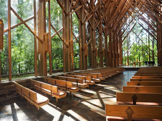A peaceful chapel interior with wooden pews and sunlight streaming through tall windows.